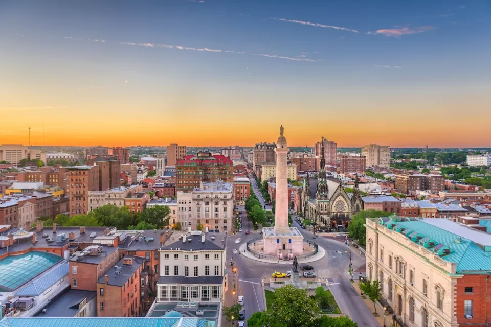 Aerial view of downtown Baltimore, Maryland with prominent statue in foreground at dusk.